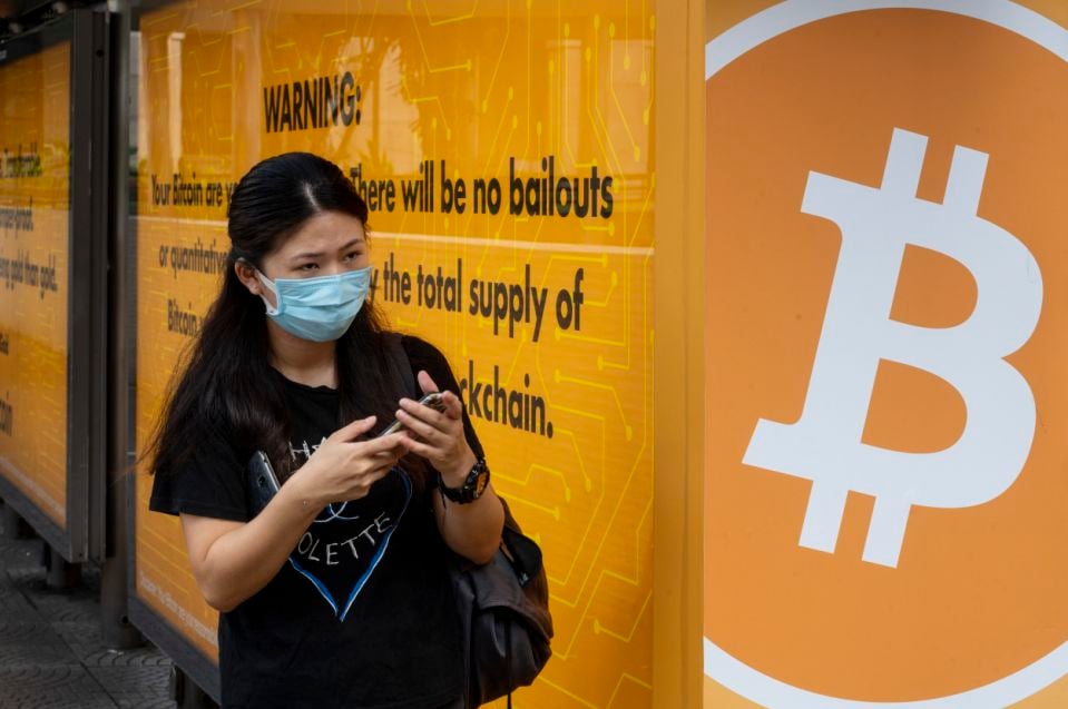 Một người phụ nữ đứng cạnh một trạm xe buýt được bao phủ bởi quảng cáo Bitcoin tiền điện tử Cryptocurrency ở Hồng Kông, ngày 24 tháng 9 năm 2020. (Ảnh của Budrul Chukrut / SOPA Images / LightRocket qua Getty Images)